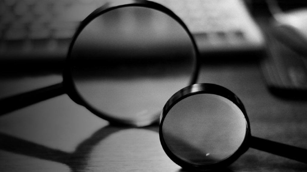 A black and white photo of two spying glasses laying on a desk